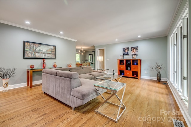 living room with baseboards, a chandelier, crown molding, light wood-style floors, and visible vents
