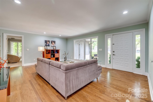 living room featuring light wood-style floors, baseboards, and crown molding