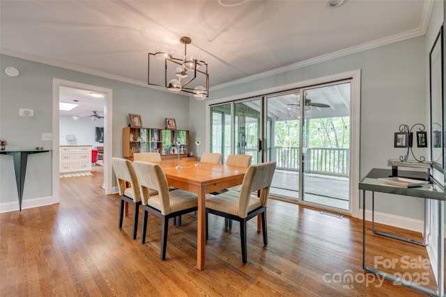 dining space featuring crown molding, ceiling fan with notable chandelier, and wood finished floors