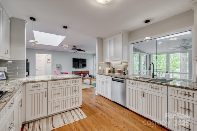 kitchen with a sink, dishwasher, ceiling fan, and a skylight