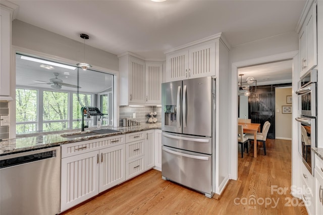 kitchen featuring light wood-style flooring, white cabinetry, appliances with stainless steel finishes, a sink, and decorative backsplash