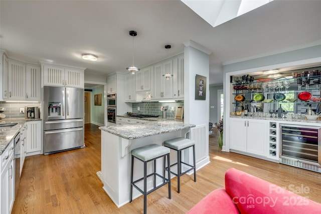 kitchen featuring backsplash, white cabinets, appliances with stainless steel finishes, and beverage cooler