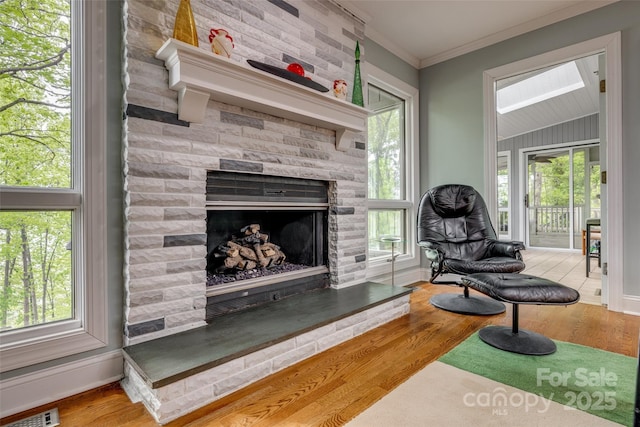 living area featuring plenty of natural light, baseboards, crown molding, and wood finished floors