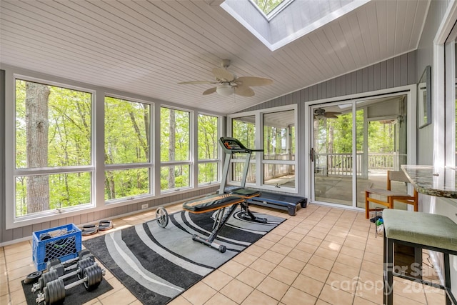 workout area featuring plenty of natural light, vaulted ceiling with skylight, a ceiling fan, and light tile patterned floors