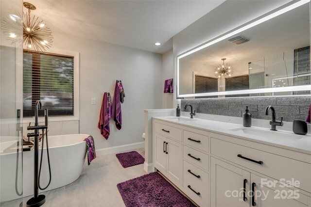 full bathroom with double vanity, a notable chandelier, visible vents, and a sink