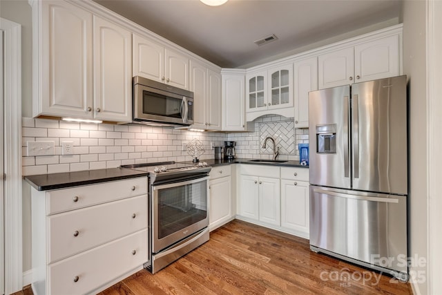 kitchen with visible vents, white cabinets, a sink, appliances with stainless steel finishes, and dark countertops