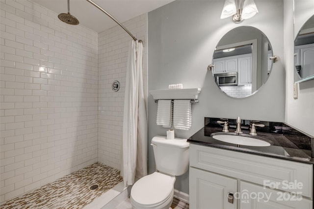 bathroom featuring toilet, vanity, and a stall shower