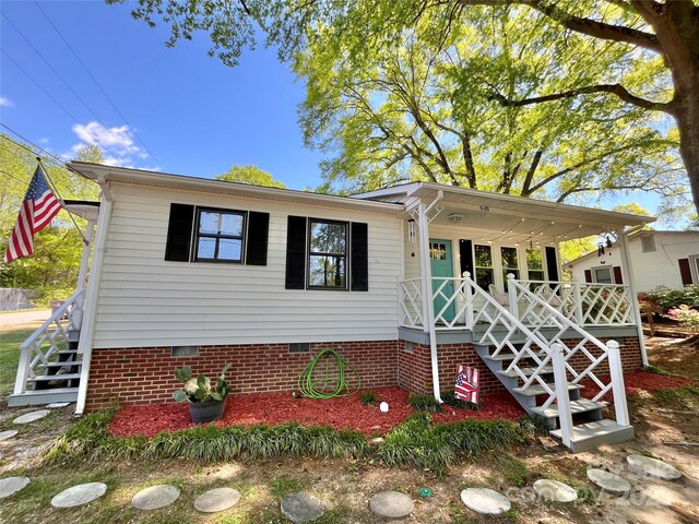 view of front facade with stairway, a porch, and crawl space