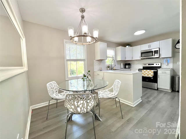 dining area with baseboards, a notable chandelier, and light wood-style flooring