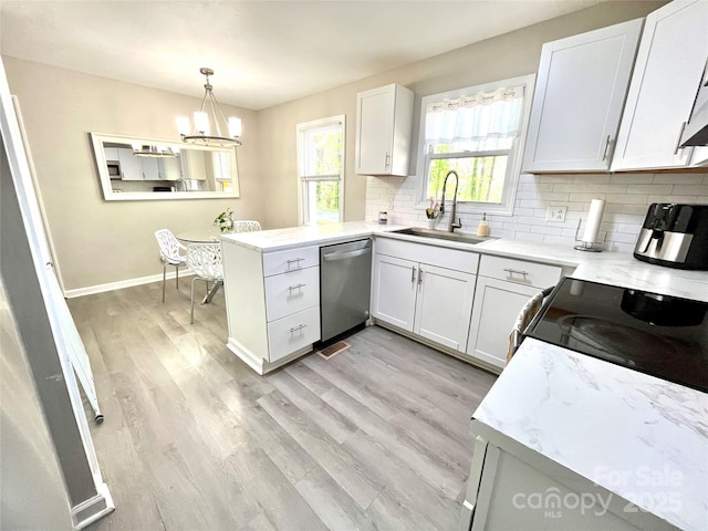 kitchen with stainless steel dishwasher, a sink, light wood-type flooring, backsplash, and a peninsula