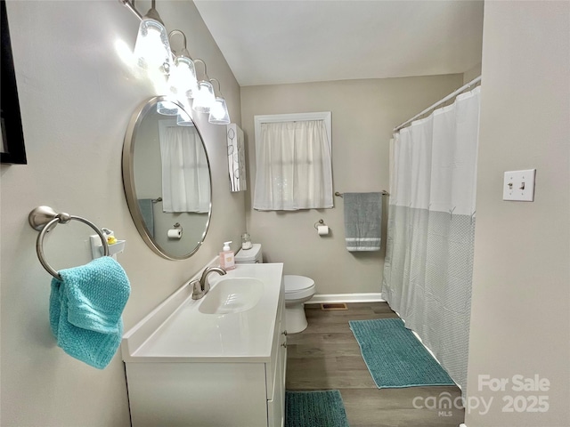 bathroom featuring toilet, visible vents, baseboards, wood finished floors, and vanity
