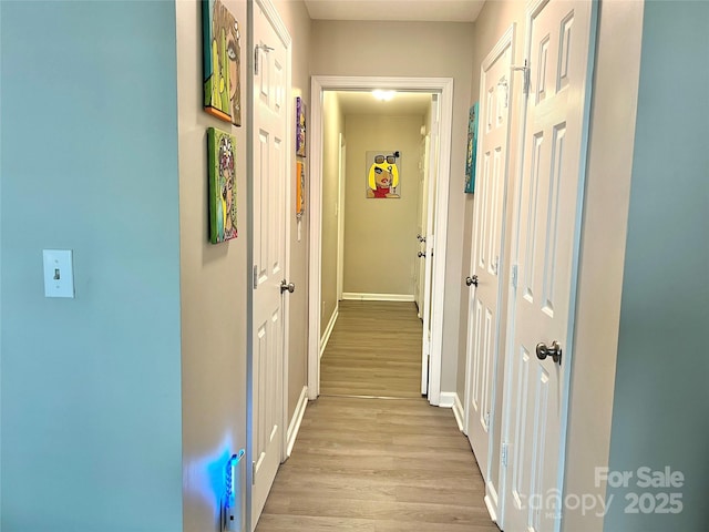 hallway featuring light wood-type flooring and baseboards