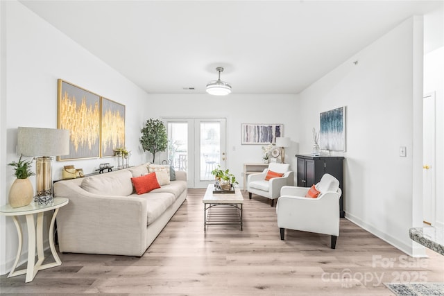 living room with light wood-style floors, french doors, and baseboards