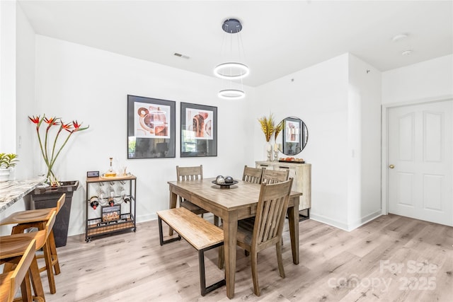 dining space featuring light wood-style floors and baseboards