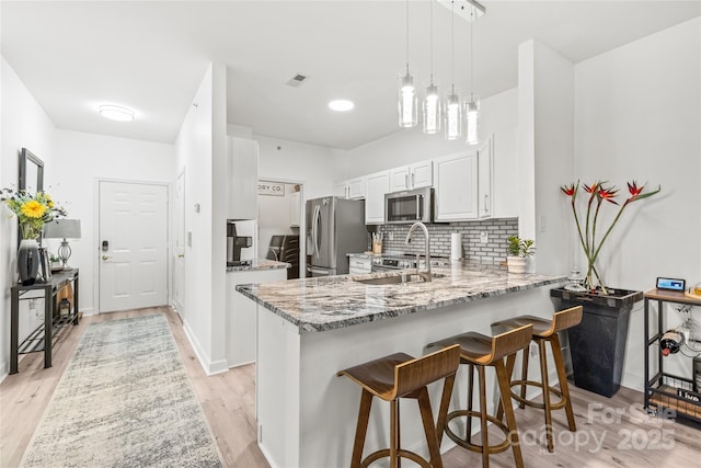 12357 Copper Mountain Blvd, Charlotte, NC 28277 - kitchen featuring appliances with stainless steel finishes, a peninsula, light stone countertops, a kitchen breakfast bar, and white cabinets