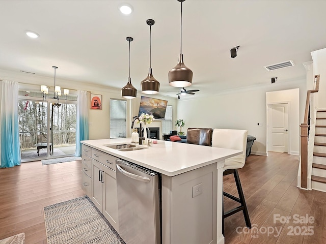 kitchen featuring light wood-type flooring, a fireplace, visible vents, stainless steel dishwasher, and a sink