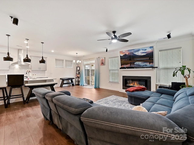 living area with a glass covered fireplace, dark wood finished floors, and ceiling fan