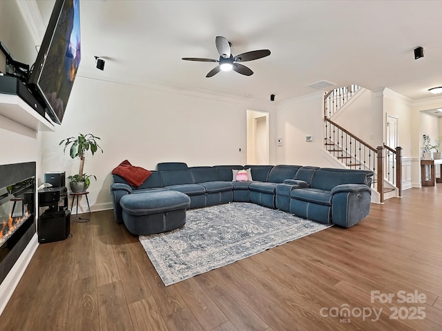 living room with ornamental molding, stairs, visible vents, ceiling fan, and wood finished floors
