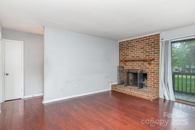 unfurnished living room featuring a brick fireplace, a textured ceiling, wood finished floors, and baseboards