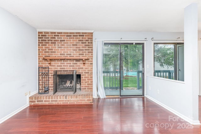 unfurnished living room with wood finished floors, a fireplace, and baseboards