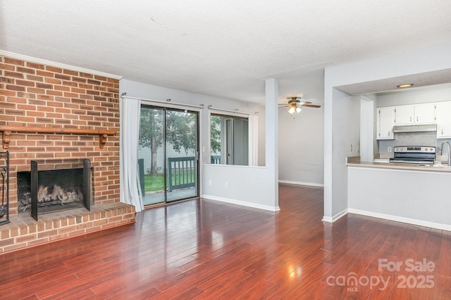 unfurnished living room with dark wood-style flooring, baseboards, and a ceiling fan