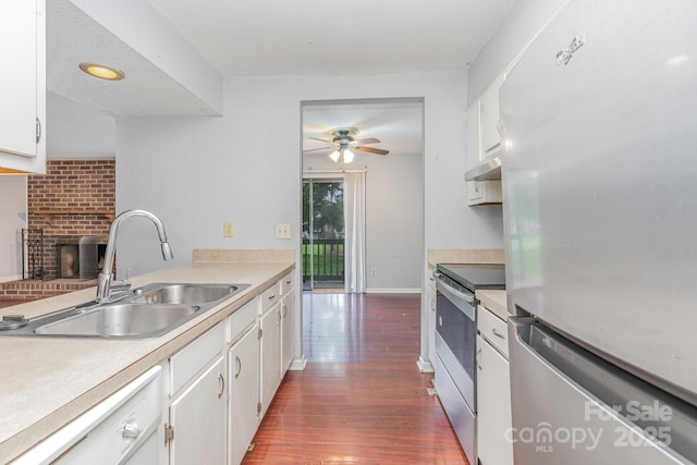 kitchen with appliances with stainless steel finishes, a fireplace, under cabinet range hood, ceiling fan, and a sink
