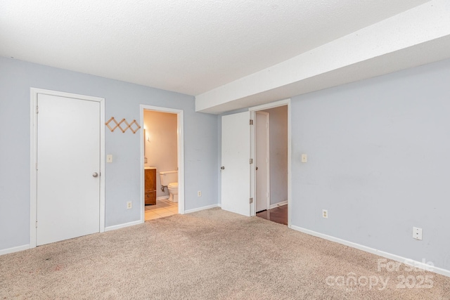 unfurnished bedroom with baseboards, carpet, and ensuite bath