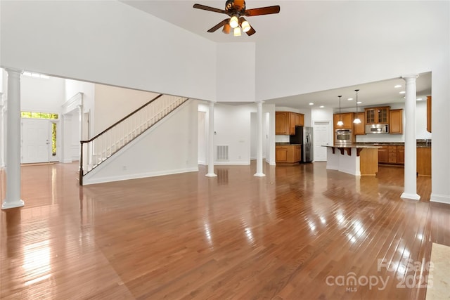 7302 Yellowhorn Trl, Waxhaw, NC 28173 - unfurnished living room with ornate columns, wood finished floors, ceiling fan, stairs, and baseboards
