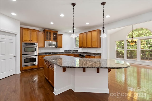 7302 Yellowhorn Trl, Waxhaw, NC 28173 - kitchen with appliances with stainless steel finishes, brown cabinets, a breakfast bar area, and recessed lighting