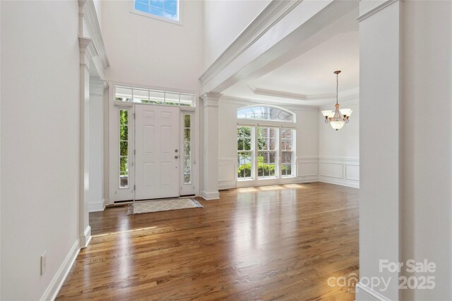 7302 Yellowhorn Trl, Waxhaw, NC 28173 - foyer entrance featuring wood finished floors, a chandelier, ornamental molding, decorative columns, and a decorative wall