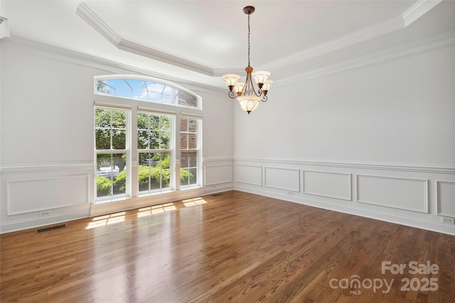 7302 Yellowhorn Trl, Waxhaw, NC 28173 - unfurnished room with a chandelier, a tray ceiling, ornamental molding, wood finished floors, and a decorative wall