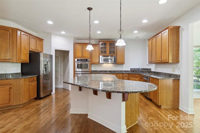 7302 Yellowhorn Trl, Waxhaw, NC 28173 - kitchen featuring appliances with stainless steel finishes, a kitchen island, recessed lighting, a breakfast bar, and brown cabinets