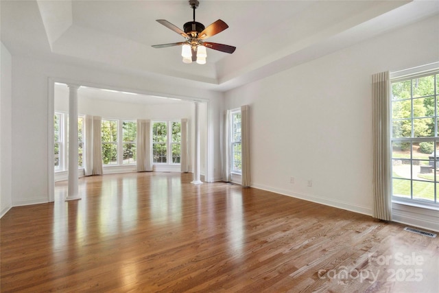 7302 Yellowhorn Trl, Waxhaw, NC 28173 - empty room with healthy amount of natural light, wood finished floors, decorative columns, and a tray ceiling