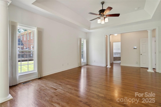 7302 Yellowhorn Trl, Waxhaw, NC 28173 - unfurnished room with ornate columns, a tray ceiling, plenty of natural light, and wood finished floors