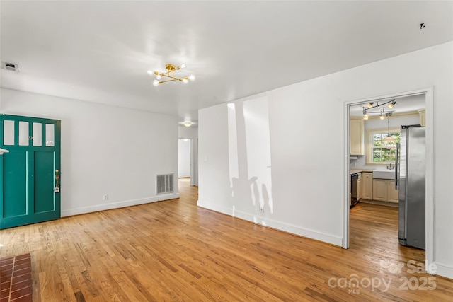 9 Canterbury Rd, Asheville, NC 28805 - unfurnished living room featuring visible vents, baseboards, an inviting chandelier, a sink, and light wood-style floors