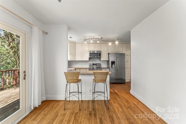 9 Canterbury Rd, Asheville, NC 28805 - kitchen with baseboards, a breakfast bar, a peninsula, light wood finished floors, and stainless steel appliances