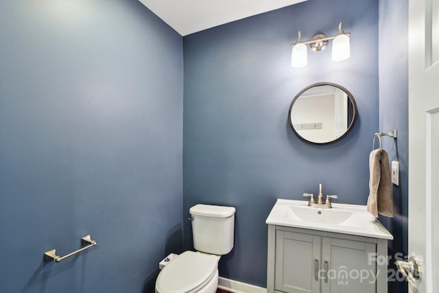 bathroom with toilet, vanity, and baseboards