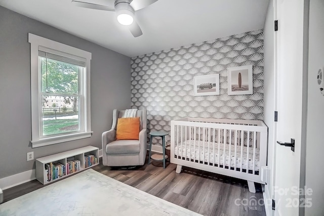 3612 Cobbleridge Dr, Charlotte, NC 28215 - bedroom featuring an accent wall, a nursery area, wood finished floors, wallpapered walls, and baseboards