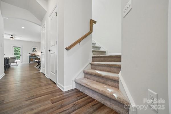 staircase featuring wood finished floors, a ceiling fan, and baseboards