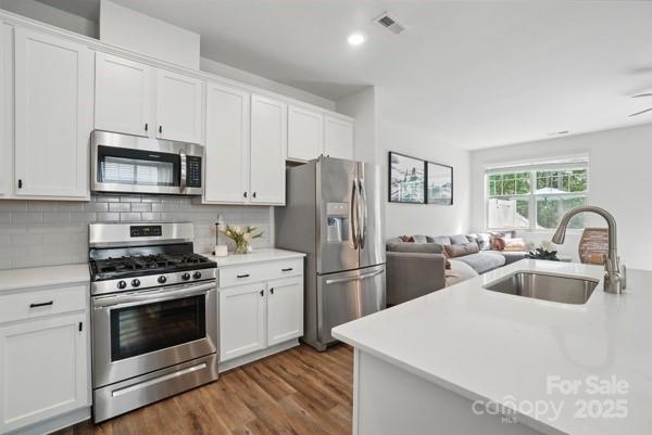 kitchen featuring white cabinetry, stainless steel appliances, light countertops, and a sink