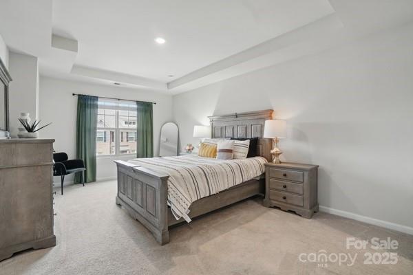 bedroom featuring light carpet, baseboards, a tray ceiling, and recessed lighting