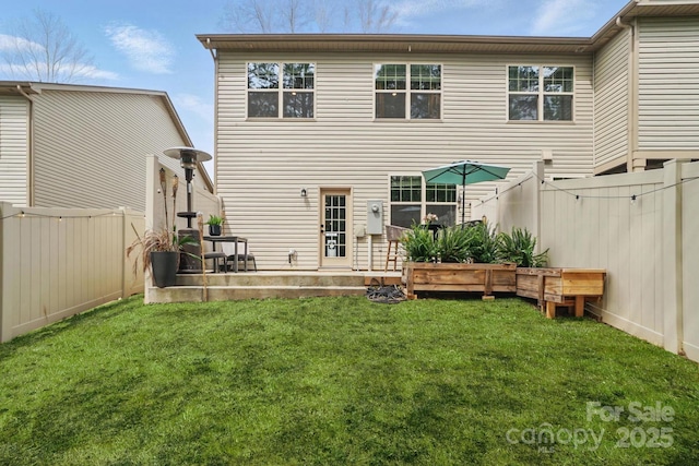 rear view of house with a yard and a fenced backyard
