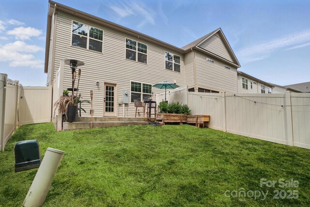 back of house featuring a gate, a yard, and a fenced backyard