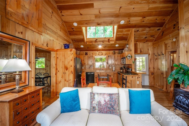 living area featuring wood walls, light wood-style floors, wooden ceiling, and lofted ceiling with skylight