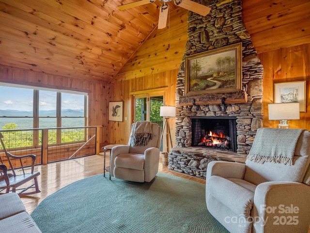 living area featuring wood walls, a stone fireplace, and wood ceiling
