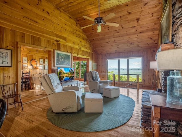 living room with high vaulted ceiling, a ceiling fan, wood ceiling, wooden walls, and hardwood / wood-style flooring