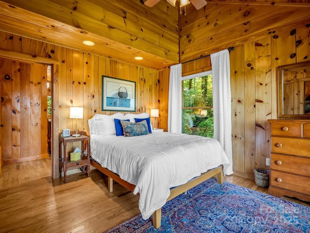 bedroom featuring wood walls, vaulted ceiling, and wood finished floors