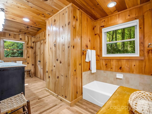 bathroom with wood walls, a bath, wooden ceiling, and plenty of natural light