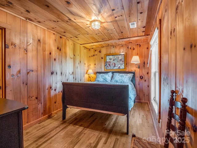 bedroom with light wood-style flooring, wooden ceiling, wood walls, and visible vents