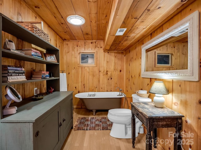 full bath with a freestanding tub, toilet, wood ceiling, wood finished floors, and wood walls